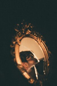 Broken Mirror Reflection - Symbol of Comparison and Self-Worth A man looking at his reflection in a cracked mirror, symbolizing the fractured self-image caused by constant comparison and self-doubt.